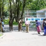 A photo of police and residents standing outside the War Memorial Hospital in Nakuru County.jpg