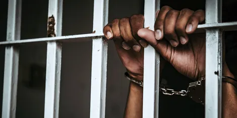 a_mans_hand_cuffed_inside_a_police_cell.jpg